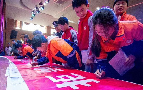 3月27日,江西抚州,金溪县锦绣小学的学生在法治安全教育课后,在“拒绝校园欺凌,共建平安校园”宣传长幅上签名。视觉中国供图