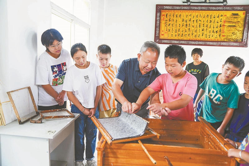 8月30日上午，在潜山市杰星桑皮纸业发展有限公司非遗传习基地，刘同烟在向研学的小朋友讲解桑皮纸制作技艺。.jpg